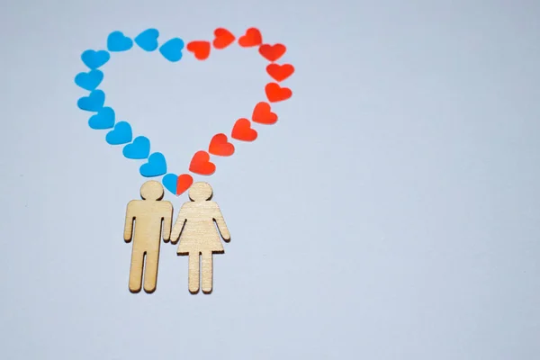 Erkek ve dişi LGBT 'yi sever. Evlilikte aile simgeleri. Bir çift sevgili. Bir kadın ve bir erkek el ele tutuşuyorlar. Kağıt mavisi ve kırmızı kalpli tahta insanlar.