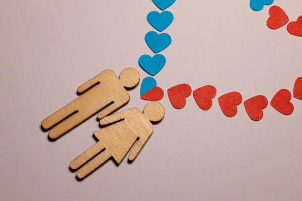 stock image Male and female love LGBT. In marriage, family icons. Couple of lovers. A woman and a man are holding hands. Wooden people with paper blue and red hearts