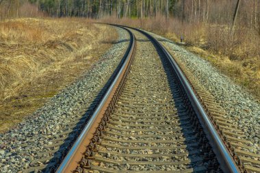 Tren için tren rayları. Kırsal bir bölgede demiryolu rayları. Demiryolu ile sanayi manzarası. İlkbaharda eski demiryolu. Köyde demiryolu olan eski bir demiryolu..