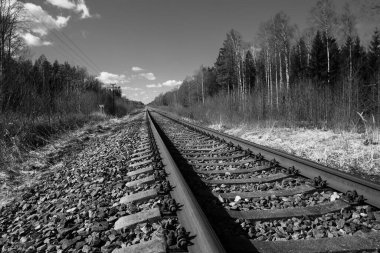 Tren için tren rayları. Kırsal bir bölgede demiryolu rayları. Demiryolu ile sanayi manzarası. İlkbaharda eski demiryolu. Köyde demiryolu olan eski bir demiryolu..