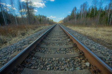 Tren için tren rayları. Kırsal bir bölgede demiryolu rayları. Demiryolu ile sanayi manzarası. İlkbaharda eski demiryolu. Köyde demiryolu olan eski bir demiryolu..