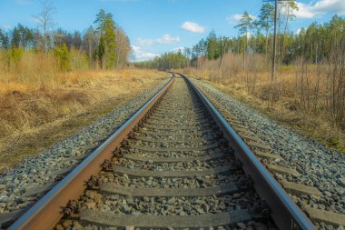 Tren için tren rayları. Kırsal bir bölgede demiryolu rayları. Demiryolu ile sanayi manzarası. İlkbaharda eski demiryolu. Köyde demiryolu olan eski bir demiryolu..