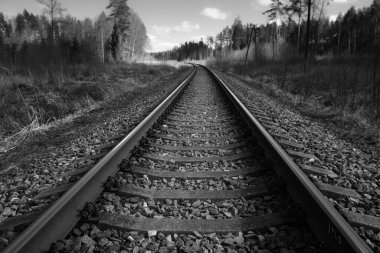 Tren için tren rayları. Kırsal bir bölgede demiryolu rayları. Demiryolu ile sanayi manzarası. İlkbaharda eski demiryolu. Köyde demiryolu olan eski bir demiryolu..