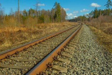 Tren için tren rayları. Kırsal bir bölgede demiryolu rayları. Demiryolu ile sanayi manzarası. İlkbaharda eski demiryolu. Köyde demiryolu olan eski bir demiryolu..