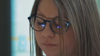 Bir kız üniversite öğrencisi bilgisayar kullanıyor. Uzaktan öğrenme çevrimiçi seminer sınıfı. Endişeli kadın bilgisayar düşünme problemini çözmeye çalışıyor. Bilgisayarda çalışan genç iş kadınının yan görünüşü