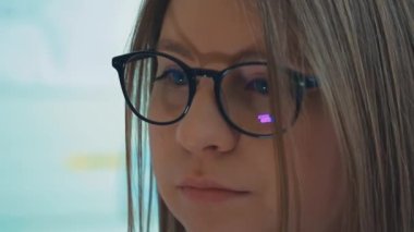 Bir kız üniversite öğrencisi bilgisayar kullanıyor. Uzaktan öğrenme çevrimiçi seminer sınıfı. Endişeli kadın bilgisayar düşünme problemini çözmeye çalışıyor. Bilgisayarda çalışan genç iş kadınının yan görünüşü