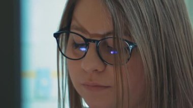 Bir kız üniversite öğrencisi bilgisayar kullanıyor. Uzaktan öğrenme çevrimiçi seminer sınıfı. Endişeli kadın bilgisayar düşünme problemini çözmeye çalışıyor. Bilgisayarda çalışan genç iş kadınının yan görünüşü