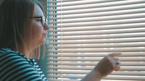 Kobieta Otwiera Żaluzje Patrzy Przez Okno Miasto Przerażona Kobieta Spoglądająca — Wideo stockowe