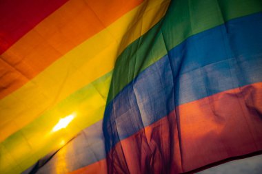 LGBT bayrağı gölün kenarında günbatımı arka planında. LGBT gay gurur bayrağı, lezbiyen, eşcinsel, biseksüel, transseksüel sosyal hareketler. Mutluluk özgürlük konsepti, eşcinsel çiftleri sevmek. Rüzgara karşı dalgalanan bir bayrak