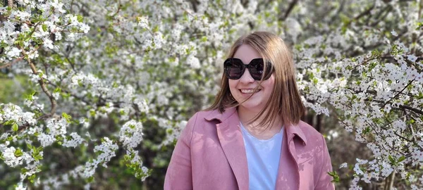 Молодая Красивая Женщина Солнечных Очках Розовое Пальто Позирует Возле Цветущей — стоковое фото