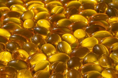 Güneş ışığında Omega kapsülleri. Güneş ışığı kapsüllerdeki balık yağını yansıtır. Doğru beslenme