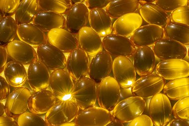 Güneş ışığında Omega kapsülleri. Güneş ışığı kapsüllerdeki balık yağını yansıtır. Doğru beslenme