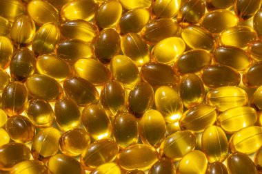 Güneş ışığında Omega kapsülleri. Güneş ışığı kapsüllerdeki balık yağını yansıtır. Doğru beslenme