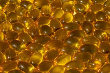 Güneş ışığında Omega kapsülleri. Güneş ışığı kapsüllerdeki balık yağını yansıtır. Doğru beslenme