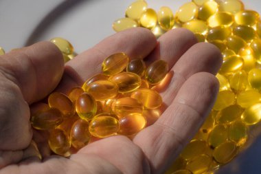 El kapsülünde balık birası var. Güneş ışığında Omega kapsülleri. Güneş ışığı kapsüllerdeki balık yağını yansıtır. Doğru beslenme