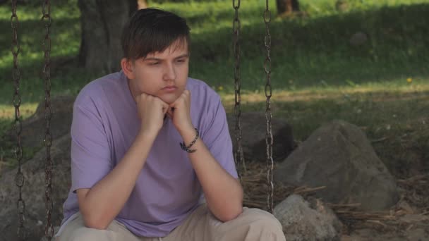 这家伙坐在秋千上情绪低落 忧心忡忡的忧郁症青少年的近视脸 不快乐的脆弱年轻人克服了压力 — 图库视频影像
