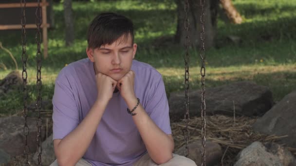 这家伙坐在秋千上情绪低落 忧心忡忡的忧郁症青少年的近视脸 不快乐的脆弱年轻人克服了压力 — 图库视频影像