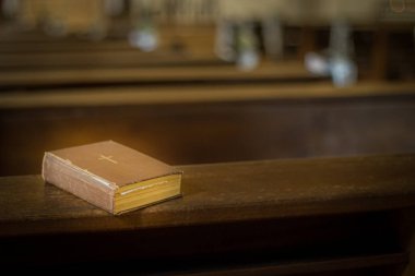 Kilise bankında İncil. Tanrı 'nın sözü küçük bir kitapta. Yumuşak seçici odaklanma. Resim için yapay olarak tahıl oluşturuldu