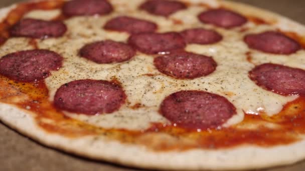 サラミとスライスしたベーコンの作品とピザ ターンテーブル上の自家製ピザ — ストック動画