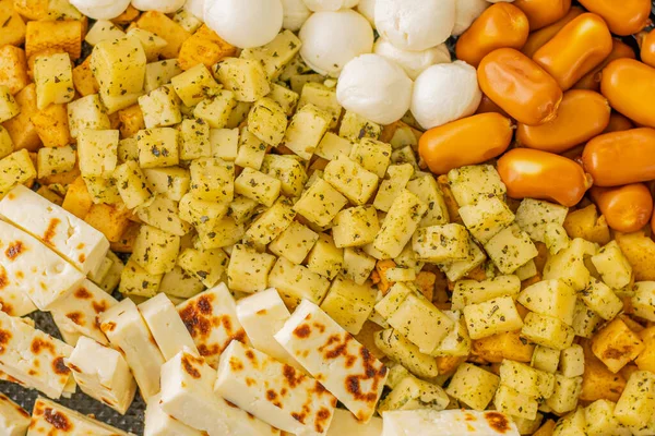 Peynirli atıştırmalıklar bir konteynırda. Farklı şekillerde dilimlenmiş peynir. Kutlama için peynir tahtası.