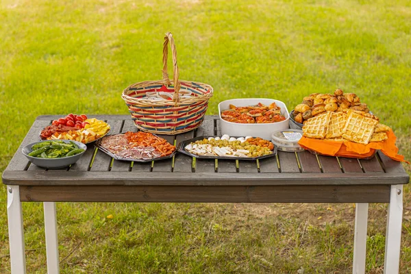Çeşitli atıştırmalıklarla piknik masası. Peynirli ve etli tatlı ve tuzlu atıştırmalıklar