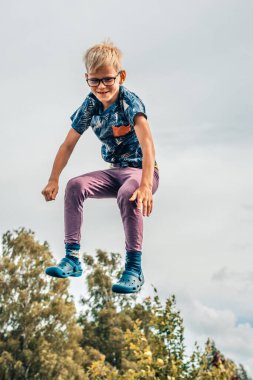 Bir çocuk trambolinde zıplıyor. Hava çocuğun atlayışında asılı kaldı. Olumlu duyguları olan bir çocuk atlar.