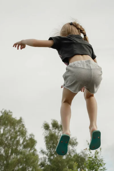 子供がトランポリンでジャンプします 少女は空気中に飛び込んだ 肯定的な感情を持つ子供がジャンプします トランポリンでジャンプすると 子供たちにとって素晴らしい楽しいアクティビティになり 物理的な促進 — ストック写真