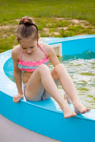 Küçük bir kız havuzda yalnız yüzüyor. Su birikintisinin yanında bir çocuk. Suyun yanında çocuk güvenliği