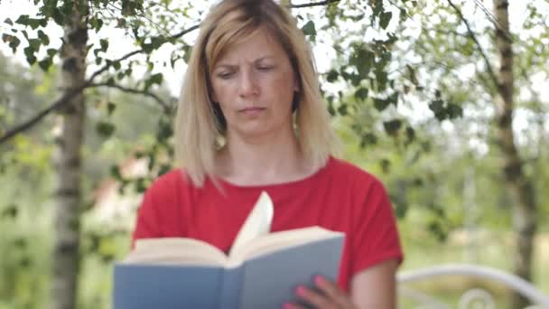 テーブルの上に本を持っている女性 女性が本を読んでいる 自宅での距離学習 — ストック動画