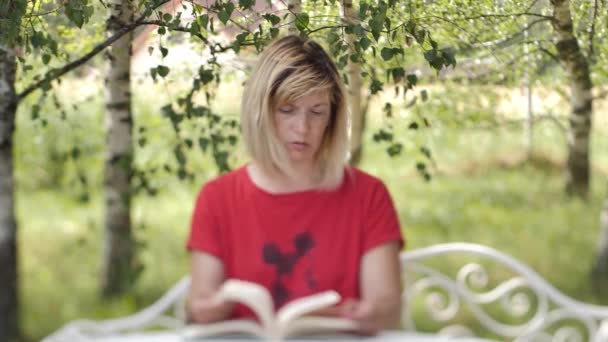 テーブルの上に本を持っている女性 女性が本を読んでいる 自宅での距離学習 — ストック動画