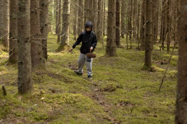 Ağzında hasır sepeti olan bir çocuk. Bir çocuk ormanda tek başına mantar topluyor. Yumuşak seçici odak