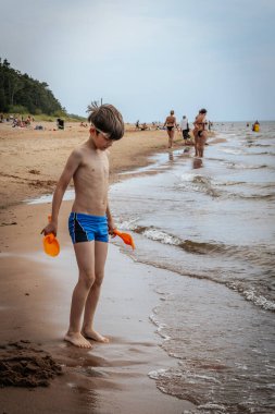 Bir çocuk deniz kıyısında kumla oynuyordu. Bir çocuk denizin kumlu sahilinde deniz kumlarıyla oynuyordu. Yumuşak seçici odak