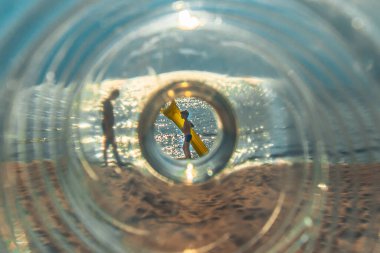 Plastik bir şişenin içinden deniz. Plastik bir şişenin içinden bir insanın görülebileceği deniz manzarasının yaratıcı bir bileşimi. Yumuşak seçici odak