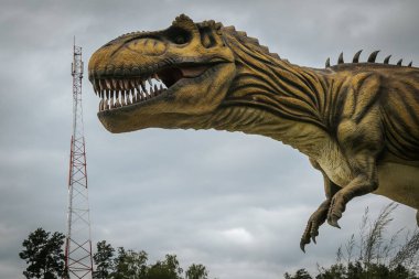 Arka planda dinozor olan bir iletişim kulesi. Harika fiyatlı sinyal kulesi. Yüksek iletişim oranlarına sahip bir kavram.