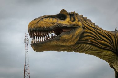 Arka planda dinozor olan bir iletişim kulesi. Harika fiyatlı sinyal kulesi. Yüksek iletişim oranlarına sahip bir kavram.