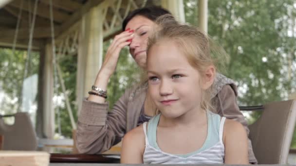 美しい目をしている少女 子供は母親とテーブルに座っている — ストック動画