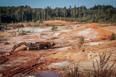 Karavanı olan ağır bir makine kum ocağında çalışıyor. Kazıcı makineye kum ve kil yükler..