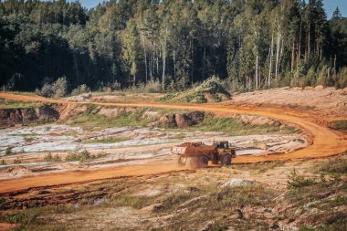 Karavanı olan ağır bir makine kum ocağında çalışıyor. Kazıcı makineye kum ve kil yükler..