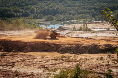 Karavanı olan ağır bir makine kum ocağında çalışıyor. Kazıcı makineye kum ve kil yükler..