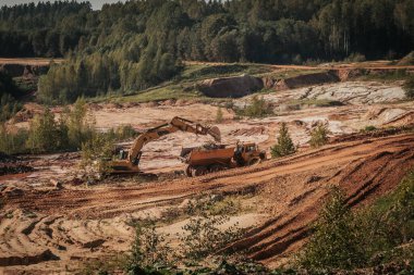 Karavanı olan ağır bir makine kum ocağında çalışıyor. Kazıcı makineye kum ve kil yükler..