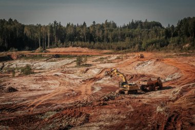 Karavanı olan ağır bir makine kum ocağında çalışıyor. Kazıcı makineye kum ve kil yükler..