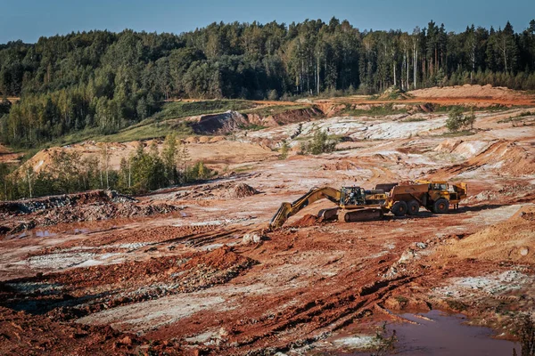 Karavanı olan ağır bir makine kum ocağında çalışıyor. Kazıcı makineye kum ve kil yükler..