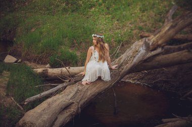 Orman Portresinde Gülümseyen Güzel Moda Modeli. Sarışın, genç bir kadın ormanda şık bir elbise giyiyor..