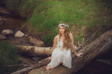 Orman Portresinde Gülümseyen Güzel Moda Modeli. Sarışın, genç bir kadın ormanda şık bir elbise giyiyor..