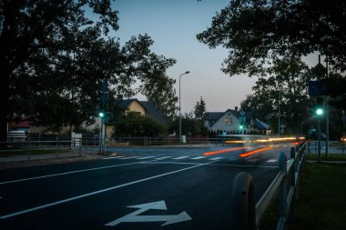 Şehir Trafiğinde Bulanık Hızlı Araba Hareketi Aydınlatılmış Işık İzleri. Hızlı bir şehir otobanındaki ışıklı arka lambaların bulanıklığı. Alacakaranlıktaki Şehir Sokağı Araba Işığı İzleri ve Yansımaları