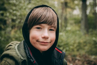 Sonbahar ormanında bir çocuk. Başında başlığı olan bir çocuk.