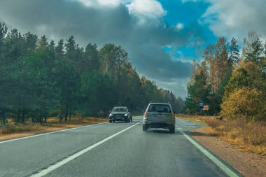 Riga karayolu trafiği asfaltlanmış. Letonya yollarında trafik. Asfalt kaplamalı yol. Ağır ve hafif araç hareketi. Yaklaşan fırtınada ağır bulutlar.