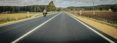 Riga - Valmiera yeni yolu asfaltladı. Letonya yollarında trafik. Asfalt kaplamalı yol. Ağır ve hafif araç hareketi.