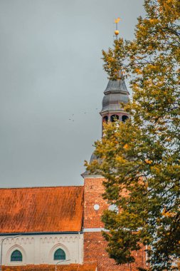 Valmiera Simanis Kilisesi Sonbaharda açık sarı yapraklarla