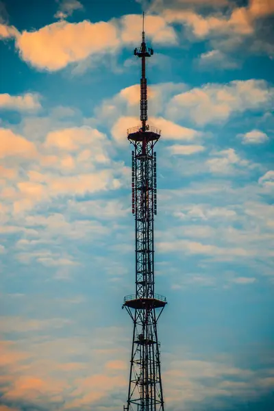 High-Rise Communications Tower Under Sunny Sky. High-tech communications tower against blue sky. A modern high-rise building with a communications tower and aerial view.